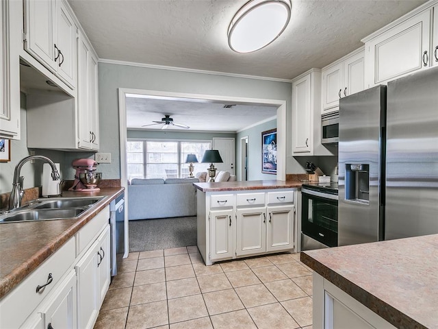 kitchen with a sink, appliances with stainless steel finishes, dark countertops, and a ceiling fan