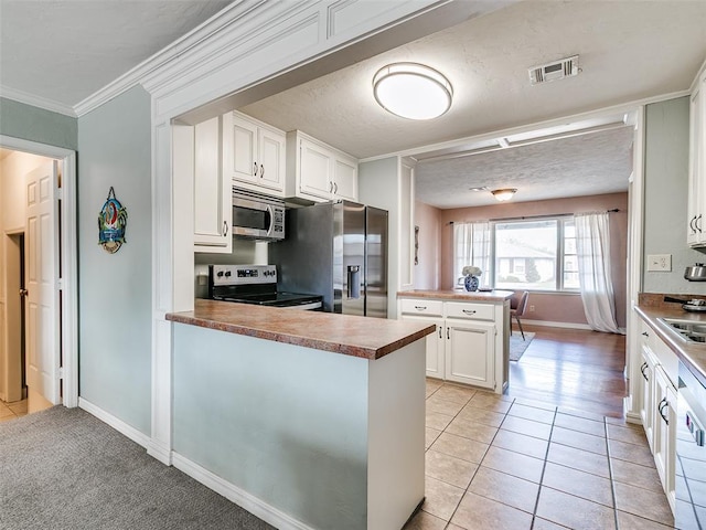kitchen featuring baseboards, ornamental molding, a peninsula, white cabinetry, and appliances with stainless steel finishes