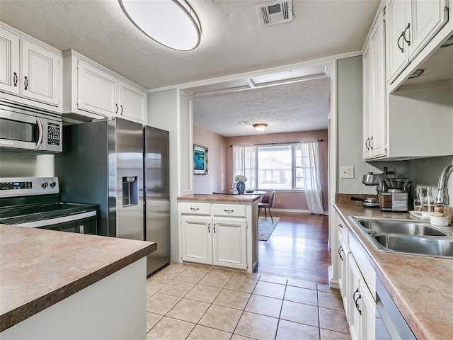 kitchen featuring a textured ceiling, white cabinetry, visible vents, appliances with stainless steel finishes, and a sink