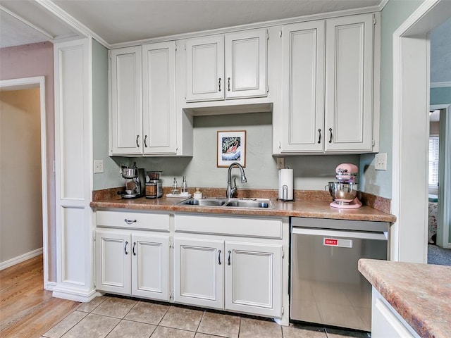 kitchen with baseboards, stainless steel dishwasher, a sink, and white cabinets