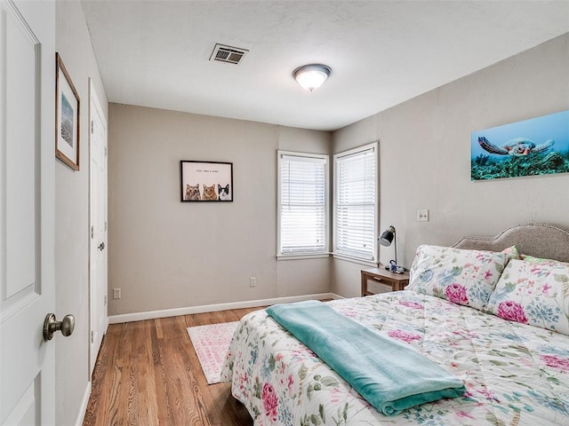 bedroom with visible vents, baseboards, and wood finished floors