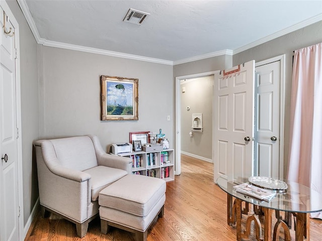 sitting room featuring ornamental molding, visible vents, light wood-style flooring, and baseboards
