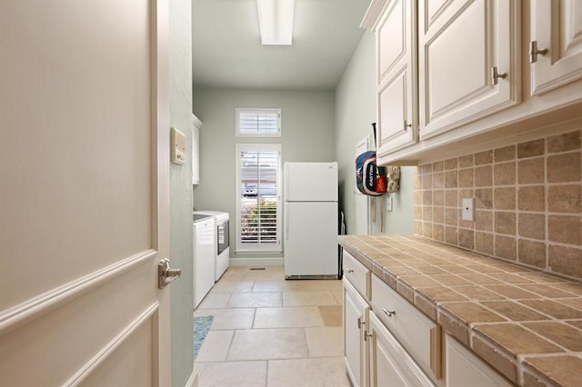 2817 Sweetbriar Way, Edmond, OK 73034 - kitchen with freestanding refrigerator, washer and dryer, tile countertops, backsplash, and light tile patterned floors
