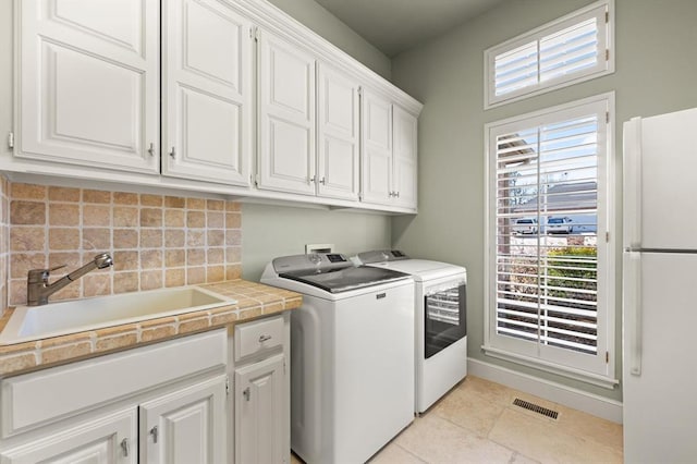 2817 Sweetbriar Way, Edmond, OK 73034 - laundry room featuring cabinet space, washing machine and dryer, light tile patterned flooring, and baseboards