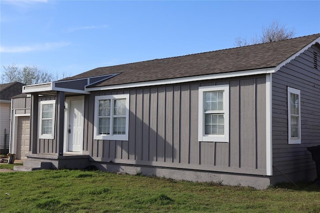 view of front of home with board and batten siding, a front yard, and a shingled roof