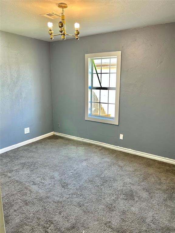 unfurnished room with baseboards, carpet floors, visible vents, and a chandelier