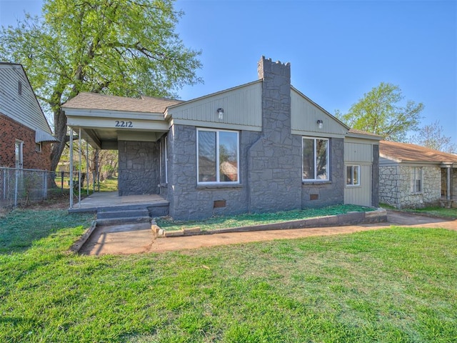 mid-century home featuring stone siding, fence, a chimney, crawl space, and a front lawn