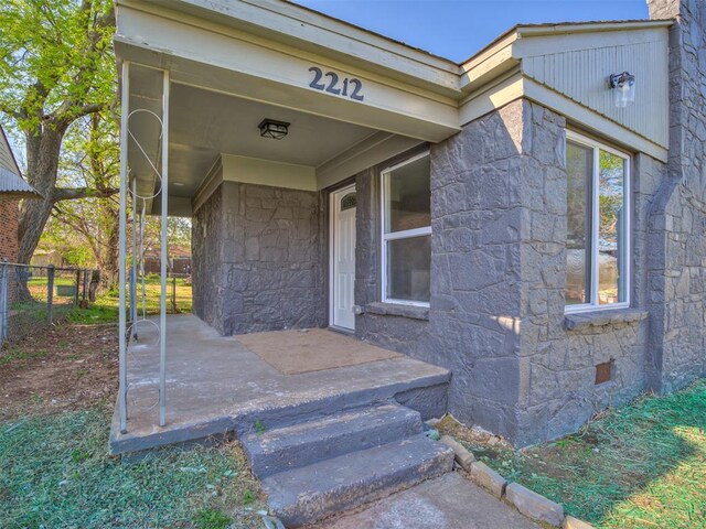 doorway to property with stone siding, crawl space, and fence