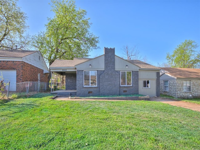back of property featuring stone siding, a yard, fence, and a chimney