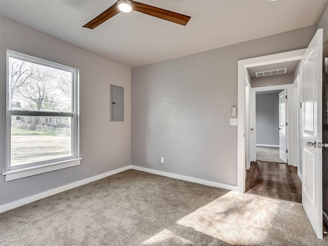 spare room with electric panel, baseboards, visible vents, and ceiling fan