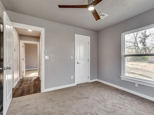 unfurnished bedroom with carpet flooring, a ceiling fan, baseboards, and visible vents