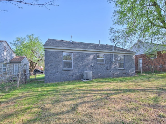back of property with fence, crawl space, stone siding, and a yard