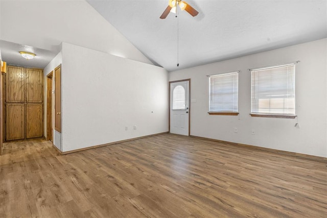empty room with vaulted ceiling, a ceiling fan, and light wood finished floors