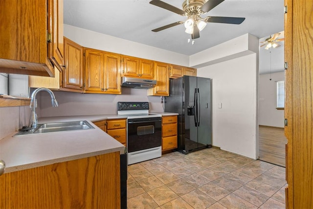 kitchen with black fridge with ice dispenser, a sink, a ceiling fan, under cabinet range hood, and range with electric cooktop