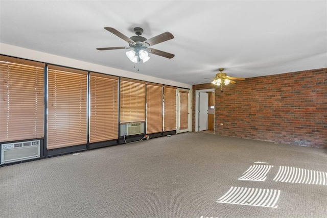 carpeted empty room with cooling unit, brick wall, and a ceiling fan