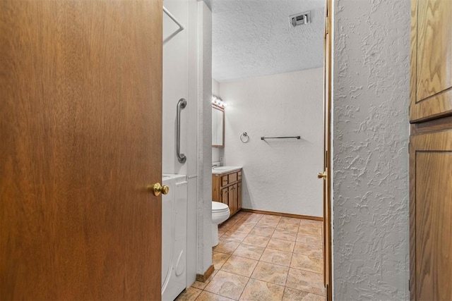 bathroom featuring vanity, a textured wall, baseboards, a textured ceiling, and visible vents