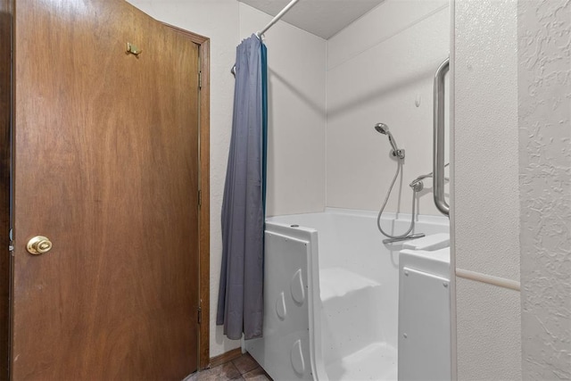 bathroom featuring a shower with shower curtain, a textured wall, and a bathtub