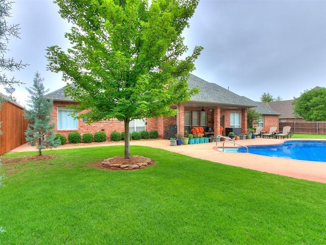 exterior space featuring a fenced in pool, fence, brick siding, a patio, and a lawn
