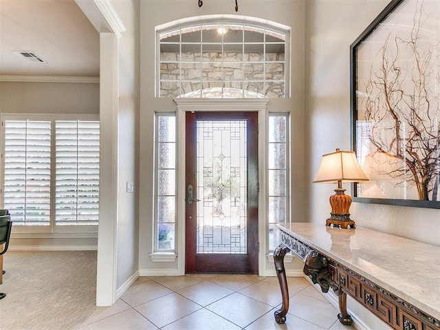 carpeted entrance foyer featuring tile patterned floors, ornamental molding, baseboards, and visible vents