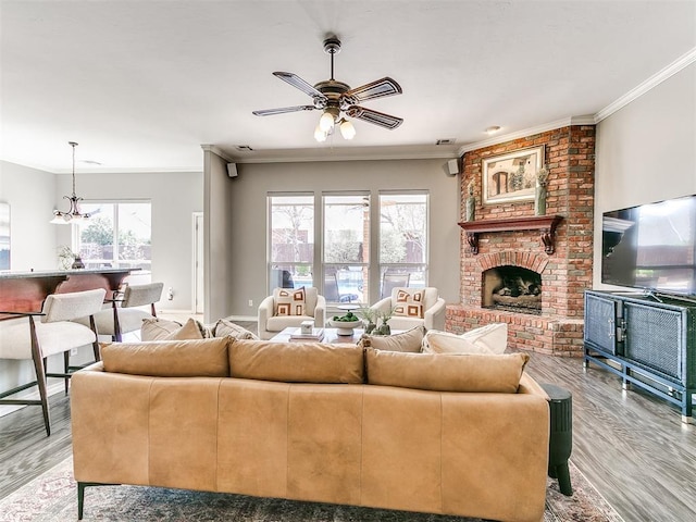 living area with ornamental molding, light wood-style floors, and ceiling fan with notable chandelier
