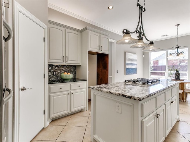 kitchen with stainless steel gas stovetop, crown molding, light stone countertops, and tasteful backsplash