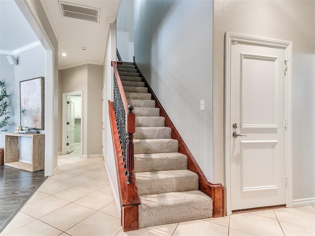staircase with tile patterned floors, visible vents, crown molding, and baseboards