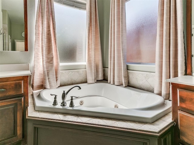 bathroom featuring plenty of natural light, a tub with jets, and vanity
