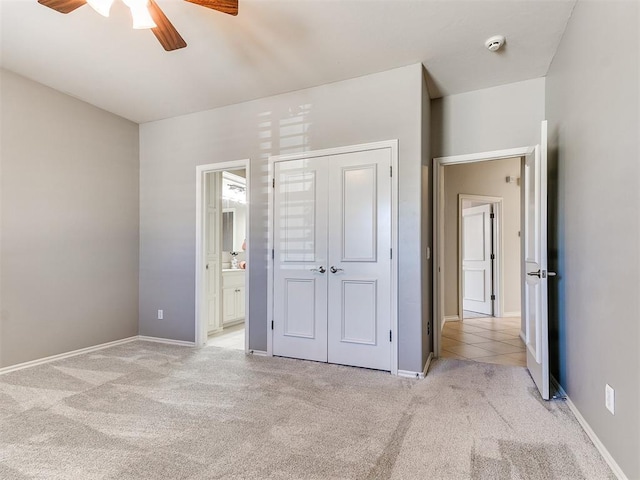 unfurnished bedroom featuring ensuite bath, a closet, light colored carpet, and baseboards