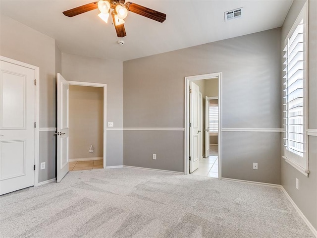 unfurnished bedroom with visible vents, baseboards, a ceiling fan, light tile patterned floors, and light colored carpet