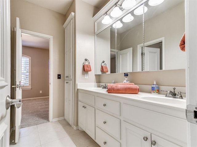 full bath featuring double vanity, a sink, baseboards, and tile patterned flooring