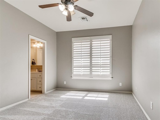 unfurnished bedroom with connected bathroom, carpet flooring, baseboards, visible vents, and ceiling fan