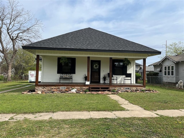 bungalow-style house featuring a front lawn, fence, a shingled roof, and a porch