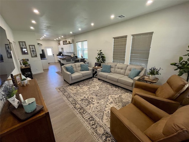 living room featuring light wood finished floors, visible vents, and recessed lighting