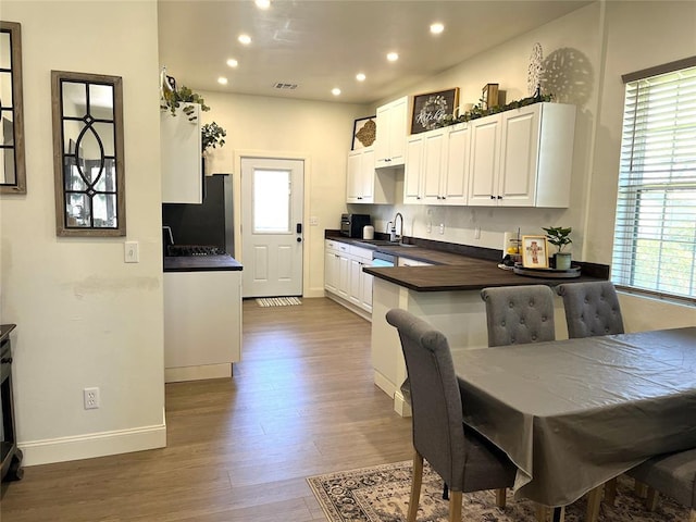 kitchen featuring refrigerator, a sink, dark countertops, visible vents, and wood finished floors