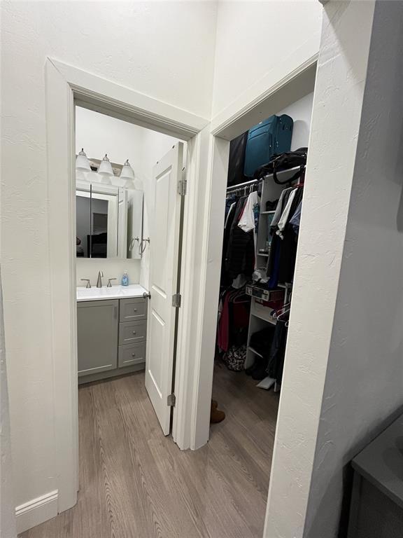 corridor with light wood-style flooring and a sink