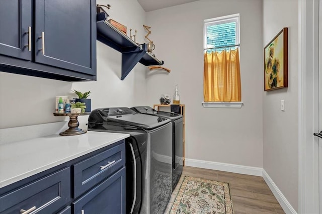 laundry area with separate washer and dryer, light wood-style floors, baseboards, and cabinet space