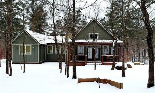 snow covered house featuring board and batten siding