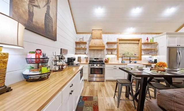kitchen featuring white cabinets, light wood-style flooring, light countertops, stainless steel appliances, and open shelves