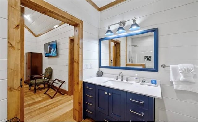 bathroom with vanity, wood walls, lofted ceiling, and wood finished floors