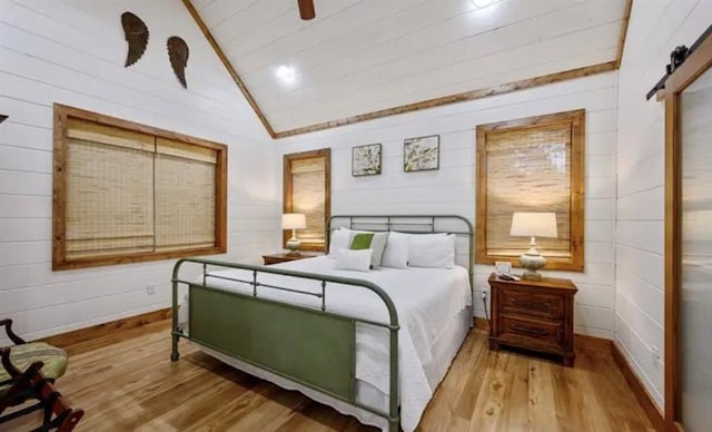 bedroom with lofted ceiling, wood finished floors, and a barn door