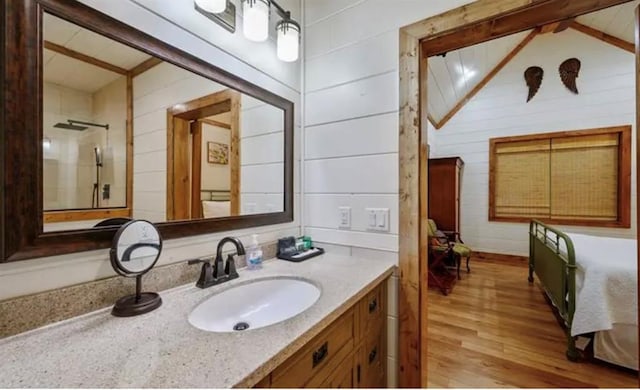 bathroom featuring lofted ceiling, wooden walls, wood finished floors, and vanity