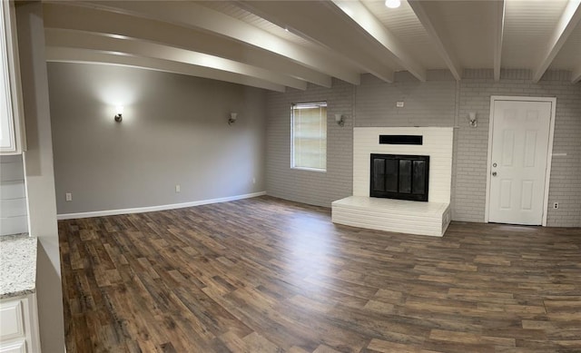 unfurnished living room with baseboards, dark wood-style floors, and beam ceiling