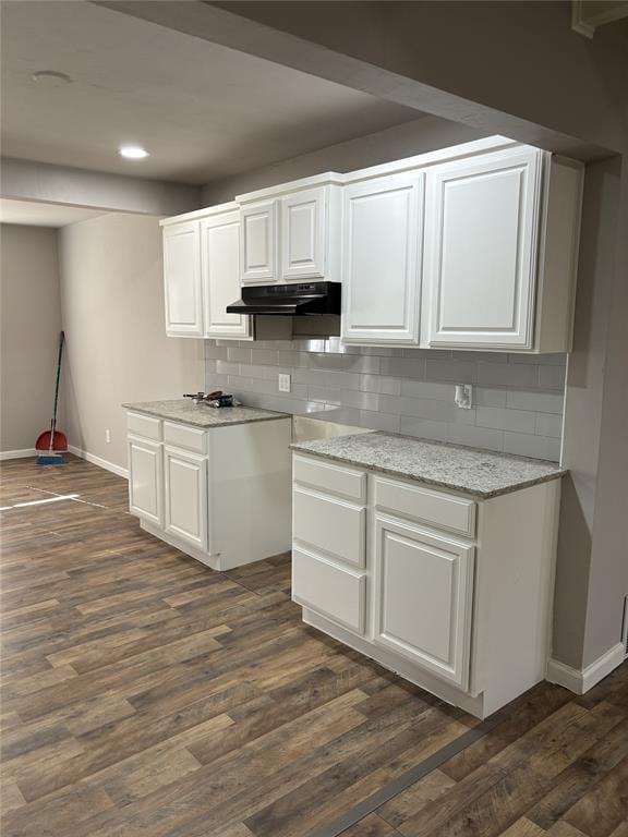kitchen featuring dark wood finished floors, baseboards, backsplash, and under cabinet range hood
