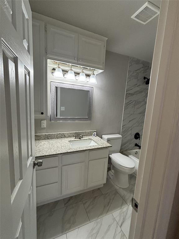 bathroom featuring vanity, visible vents, toilet, marble finish floor, and washtub / shower combination