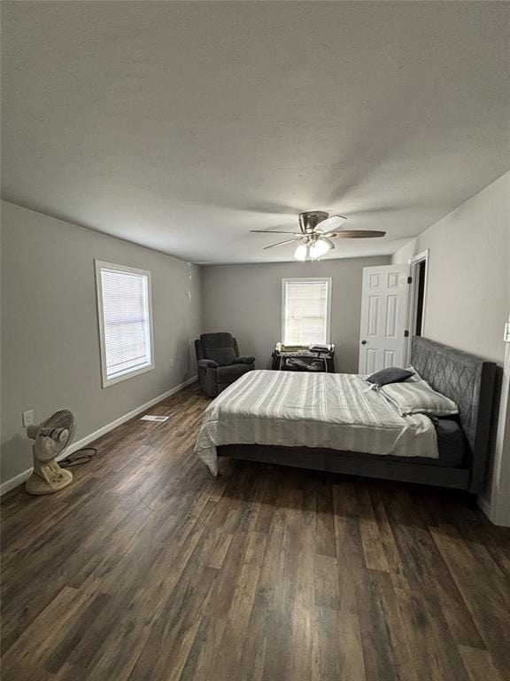bedroom with dark wood-type flooring, multiple windows, and baseboards