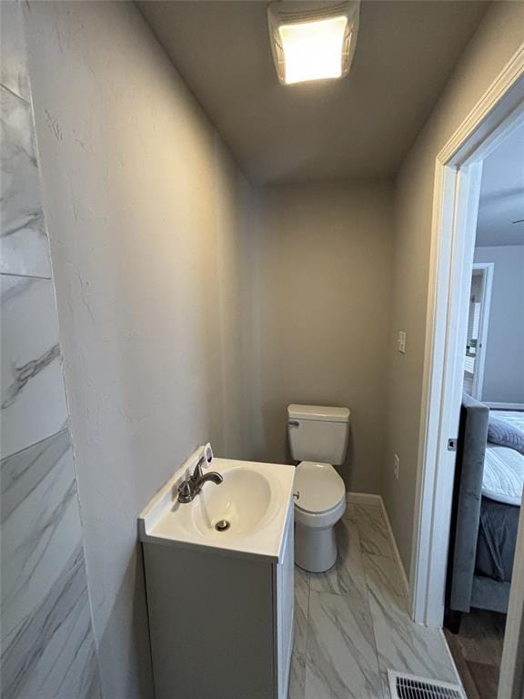 bathroom featuring visible vents, baseboards, toilet, vanity, and marble finish floor
