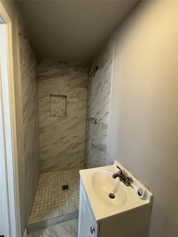 full bath featuring vanity, marble finish floor, and a stall shower