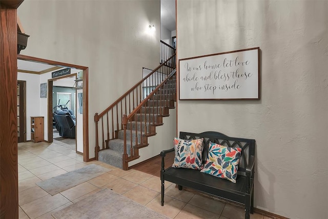 staircase featuring a textured wall, tile patterned flooring, and baseboards