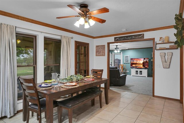 dining room with light carpet, a ceiling fan, ornamental molding, and plenty of natural light