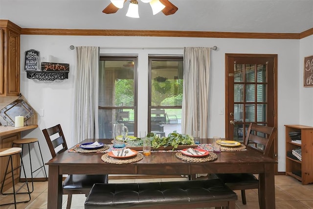 dining space with a ceiling fan, ornamental molding, and light tile patterned flooring